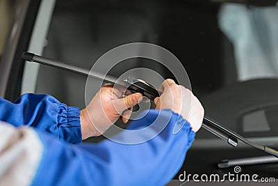 Technician is changing windscreen wipers on a car station. Stock Photo