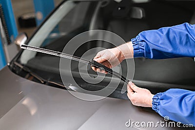 Technician is changing windscreen wipers on a car station. Stock Photo