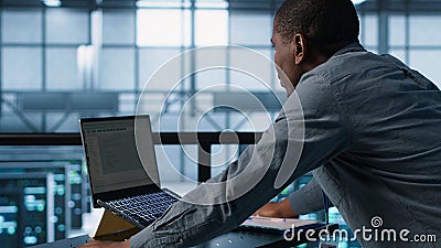 Technician coding on laptop in data center, managing server virtualization Stock Photo