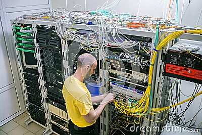 A technician connects Internet backbones with a central router. Worker lays telecommunication cables in the server room. A man Stock Photo