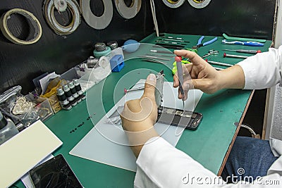 A technician disassembling a mobile phone in his small taller Stock Photo