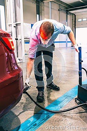 A technician doing an emission control of a security inspection of a vehicle protected with a mask and gloves to prevent the Stock Photo