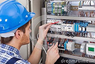 Technician examining fusebox with multimeter probe Stock Photo