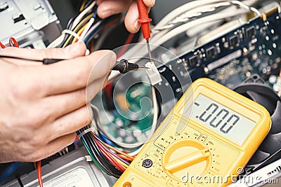 Technician hands with voltmeter above computer motherboard. Repair of computers concept. Toned with selective focus Stock Photo