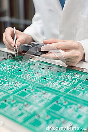 Technician inserting electronic components into a PDB for assembly Stock Photo