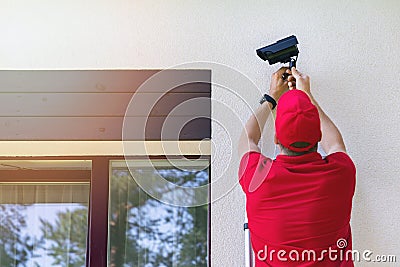 Technician installing outdoor security surveillance camera on house exterior wall Stock Photo
