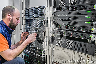 A technician installs a new hard disk into a powerful server. The system administrator replaces the data disk. A Stock Photo