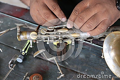 The technician man is repairing the vintage style saxophone instrument. Stock Photo