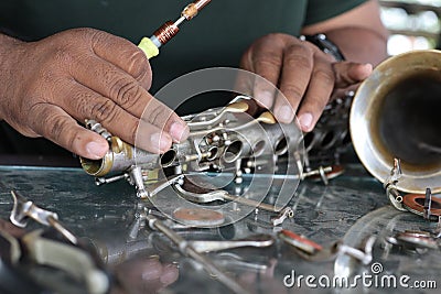 The technician man is repairing the vintage style saxophone instrument. Stock Photo