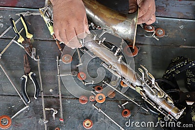 The technician man is repairing the vintage style saxophone instrument. Stock Photo