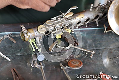 The technician man is repairing the vintage style saxophone instrument. Stock Photo