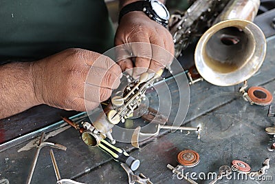 The technician man is repairing the vintage style saxophone instrument. Stock Photo