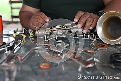 The technician man is repairing the vintage style saxophone instrument. Stock Photo