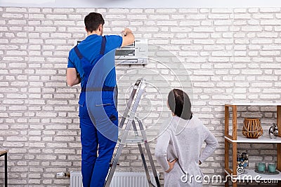 Technician Repairing Air Conditioner With Digital Multimeter Stock Photo