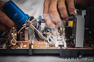 technician is repairing a circuit board, By using a soldering iron and lead coils Stock Photo