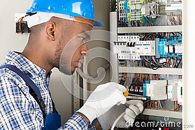 Technician Repairing Fusebox With Screwdriver Stock Photo