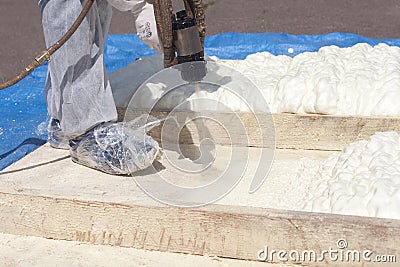 Technician spraying foam insulation using Plural Component Spray Gun. Stock Photo