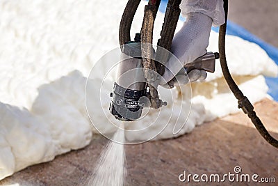 Technician spraying foam insulation using Plural Component Spray Gun. Stock Photo