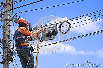 Technician on wooden ladder is installing fiber optic system in internet splitter box on electric power pole aga Stock Photo