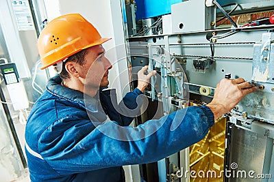 Technician worker adjusting elevator mechanism of lift Stock Photo