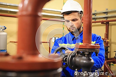 Technician worker turns valve on industrial heating boiler Stock Photo