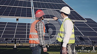 Technicians discussing solar panel array outside Stock Photo