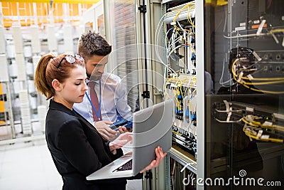 Technicians using laptop while analyzing server Stock Photo