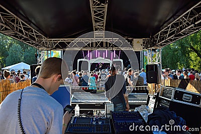 Technicians at work and People enjoying beautiful weather at festival and watching a band performing Editorial Stock Photo