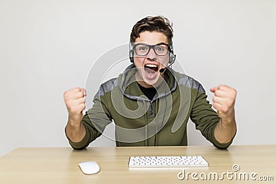 Technology, gaming, entertainment, let`s play and people concept - happy young man in eyeglasses with headset playing and winning Stock Photo