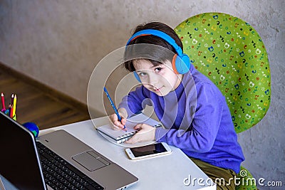 Technology, home education and people concept - boy in headphones having classes trough internet on laptop computer at home. Stock Photo