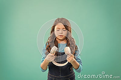 Technology for kids. Little girl holding earphones on blue background. Small child using stereo sound technology. New Stock Photo