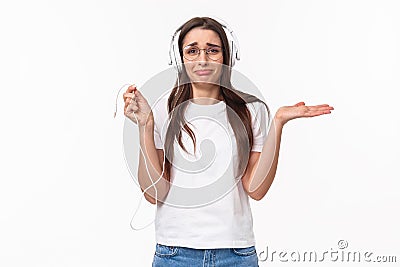 Technology, lifestyle and music concept. Portrait of awkward and frustrated young gloomy girl in headphones, holding Stock Photo