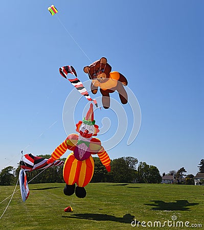 Teddy Bear and Clown Kites airborne blue sky grass and trees Stock Photo