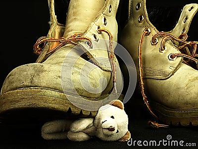 Teddy bear crushed by a heavy, old military boot. Stock Photo