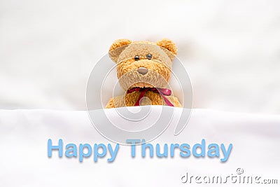 Teddy Bear lying in the white bed with message Happy Thursday Stock Photo