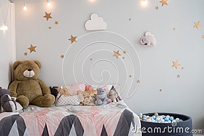 Teddy bear between paper bags and wooden chairs in child's room with pastel lamp above table Stock Photo