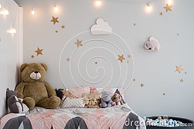 Teddy bear between paper bags and wooden chairs in child's room with pastel lamp above table Stock Photo