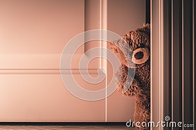 Teddy bear peeking out of the door Stock Photo