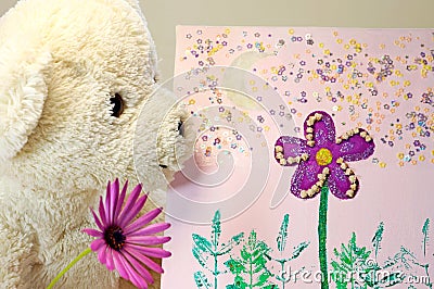 Teddy bear with a purple flower looking at a painting Stock Photo