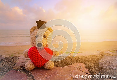 Teddy Bear with red heart sitting near the beach Stock Photo