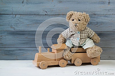 Teddy bear sitting on the toy wooden train, wooden background Stock Photo