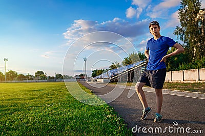 Teen boy boy does physical exercises at the stadium track, a soccer field with green grass - concept of sports and health Stock Photo