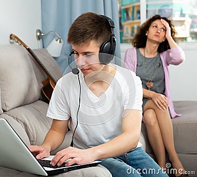 Teen boy with laptop oblivious to anxious mother Stock Photo