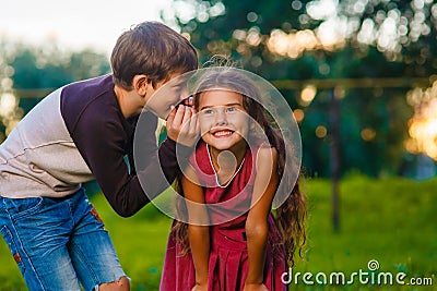 Teen boy whispering secret gossip girl child's ear Stock Photo