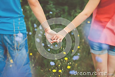 Teen couple holding hands in flower field Stock Photo