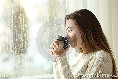 Teen drinking coffee looking through a window a rainy day Stock Photo