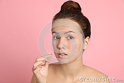Teen girl applying acne healing patch on pink background Stock Photo