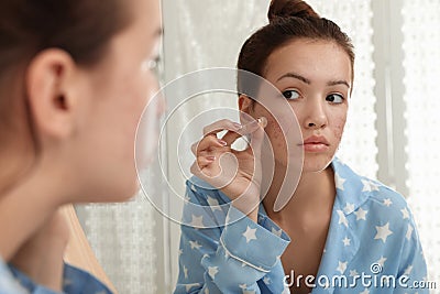 Teen girl applying acne healing patch near mirror Stock Photo