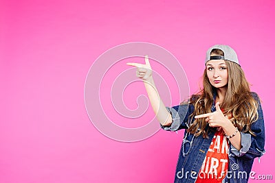 Teen girl in cap pointing at side and showing by fingers. Stock Photo
