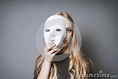 Teen girl hiding face behind mask Stock Photo